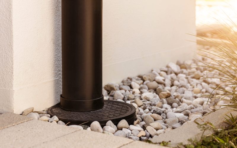 French drain Water Drainage pipe with water Stones Gravel aroud House